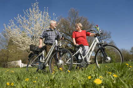 Senioren Paar mit Elektro-Fahrrad auf der Wiese